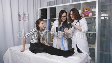 两名女医生在看一名少女手上的x光片。