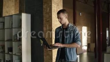 迷人的集中精力的年轻商人手里拿着一台笔记本电脑走路，打字。 白人积极分子