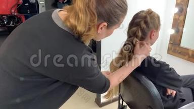 理发师编辫子的女人在美发沙龙`头发。