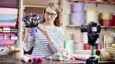在花店里，年轻的花店女用纸包花。 她试图谱写花朵