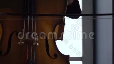女孩坐在靠近窗户的椅子上玩大提琴。 关门