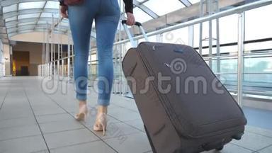 女商人带着行李穿过候机厅的腿。 穿着高跟鞋走路的女孩面目全非