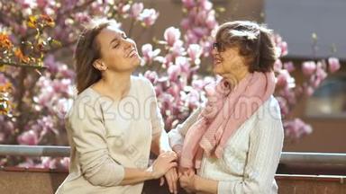 成年母亲和女儿<strong>站</strong>在阳台上谈论一朵盛开的玉兰花。 <strong>国际</strong>妇女`日