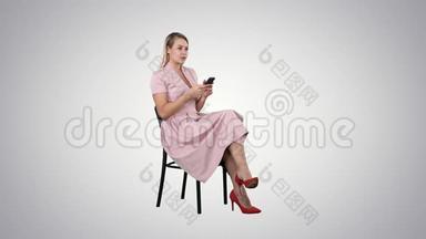 体贴的女人穿着<strong>粉色</strong>连衣裙，在<strong>渐变</strong>背景下用智能手机发短信。