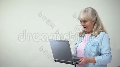 一位老太太惊讶于笔记本电脑上的信息，这是为退休人员提供的现代技术