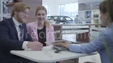 穿着时尚西装的汽车经销商在平板电脑上向年轻的成<strong>功夫</strong>妇展示他们的新车的信息。 汽车