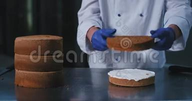 一个穿着厨师服装的大面包师的特写镜头，将奶油蛋糕的下半部分和非奶油蛋糕的上半部分放在上面