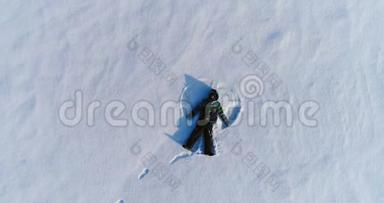 七岁的男孩做雪天使，空中镜头。 摄像机慢慢接近。