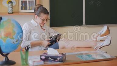 年轻女子老师坐在教室里玩手机游戏。 老师写短信。 慢动作