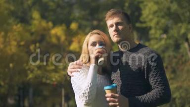 情侣们在公园里品尝热饮，拥抱，浪漫约会，喝咖啡