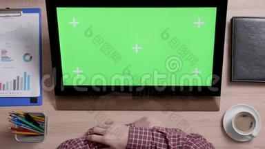 一个男人的手的俯视图触摸到触摸屏上绿色屏幕的右上角