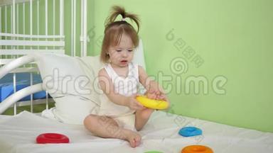 小宝宝正坐在医院病房的床上玩玩具.. 生病的女孩在医院里康复