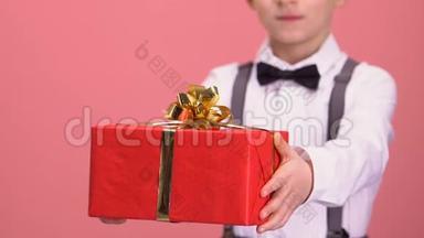 穿西装的男孩展示礼品盒供相机，庆祝和祝贺，节日