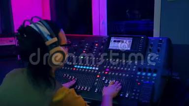 女DJ在彩色照明混合控制台工作