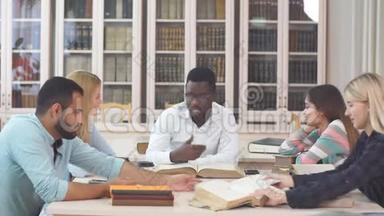 多种族的年轻人坐在桌子旁阅读参考书以作<strong>学习笔记</strong>。 在校青年学生群体