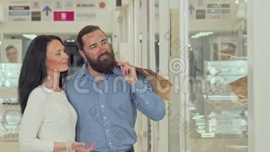 快乐的成熟夫妻在购物中心看服装店的橱窗