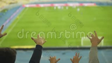 男、男、女球迷在体育场握手，为足球队的胜利欢呼