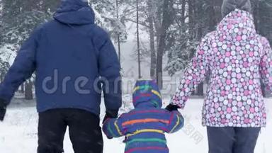 冬天降雪时，一个幸福的家庭牵着手向森林跑去。 自然休闲、旅游和游戏