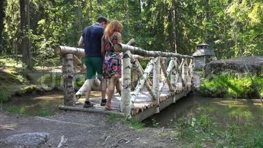一对年轻夫妇走在公园的木桥上