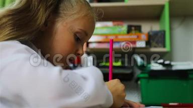 一个在书桌前<strong>穿校服的学生</strong>用粉红色铅笔写字