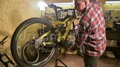 一名自行车技师在自行车修理店的长凳上修理一个山地自行车轮。 自行车修理