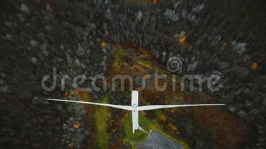 无人机向后移动，倾斜，揭示风车涡轮在冬季森林工作，可再生能源的未来概念。