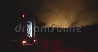 开着闪烁灯的消防车。 森林火灾时在野外焚烧草地背景下的消防车。 救援和救援