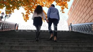 年轻时尚的一对男女走上楼梯。 学生的腿在秋天爬上旧的城市复<strong>古楼</strong>梯