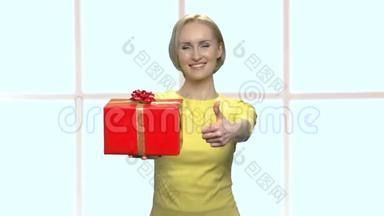 女人展示礼品盒和拇指向上。