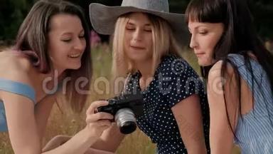 三个年轻漂亮的女孩在野餐。 摄影师在两个模特的无镜相机上拍照。 模型