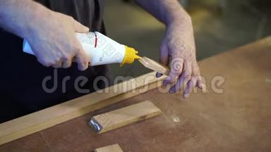 无法辨认的木匠将胶水涂在木制品上。 手工制作概念
