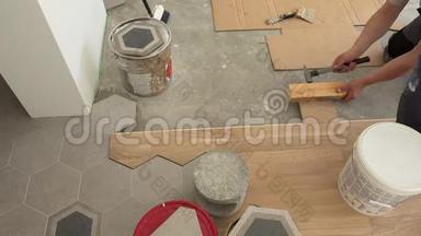 熟练工人铺设镶木地板。 男人用锤子打板