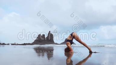 日落时分的女子<strong>瑜伽</strong>练习。 勇女慢动作在美丽的海滩上<strong>倒立</strong>做<strong>瑜伽</strong>运动