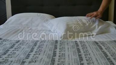 酒店客房的准备工作.. 在酒店房间或豪华的家中为刚铺好的床抚平枕头。 酒店