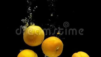 成熟的杏子在黑色的背景下落入透明的水中