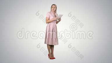 穿着粉色衣服的女青年女士站在平板电脑上，在渐变背景下给相机演讲。