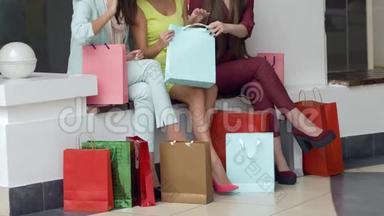 购物者的生活方式，女孩们在旺季逛完时尚商店后，考虑在腿边的纸袋里购物