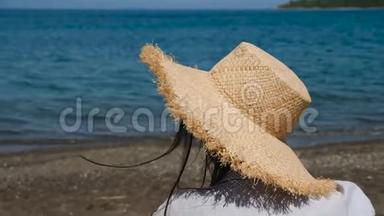 穿着衬衫戴着<strong>帽子</strong>的女孩坐在沙滩上的<strong>遮阳</strong>伞下