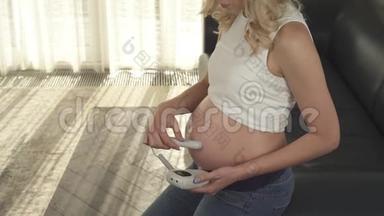 一个怀孕的金发女郎的侧视，她正在<strong>检查胎儿</strong>的心跳。 她看着肚子，微笑着。