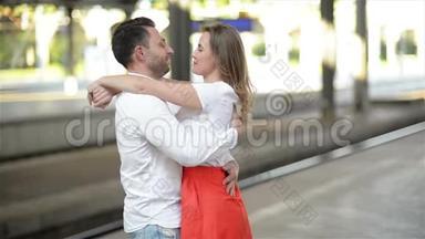 幸福情侣拥抱火车站站台。 在火车站告别，年轻女孩和男人在拥抱