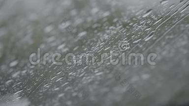 近距离观看水滴落在玻璃上。 雨水从窗户上流下来。 雨季，秋天。 雨水滴下来