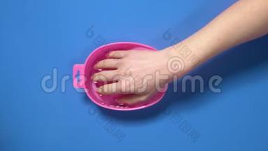 在美甲前，女人把手伸进指甲浴，为剪下的指甲做准备，在美容院，美甲水疗中心