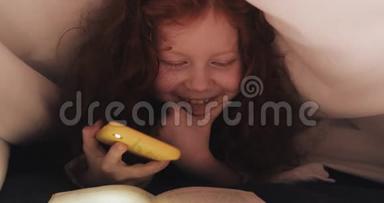 小红发女孩饶有兴趣地躺在他家的床上看书。女孩用智能手机的手电筒
