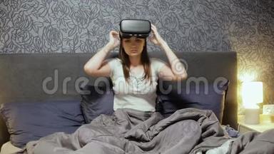 美丽的年轻女子戴着<strong>VR</strong>耳机在床上。 环顾四周，微笑，用手做手势。 观看<strong>VR</strong>视频