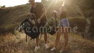 徒步旅行夫妇。年轻的男女徒步旅行者从地上捡起背包。准备出发，享受他们的时光