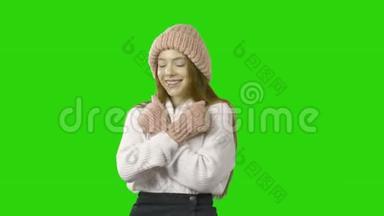 一个身穿粉色针织帽子和针织粉色手套的年轻红发少女，用微笑和微笑来表达情感