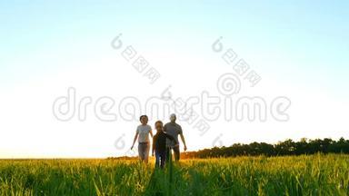 幸福的年轻家庭走在绿色的草坪上，在夕阳的背景下，慢动作。 孩子跑在爸爸妈妈前面