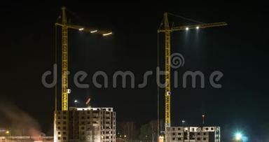 一幢多层建筑的建筑工地上，两架起重机在夜间冒烟时的剪影