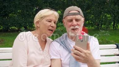 在公园里热的时候，老人夫妇用粉红色的便携式呼吸机连接在手机上降温