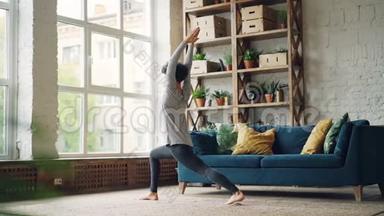 女瑜伽教练<strong>独自在家</strong>练习，做站立在地板上和移动身体的体式。 健康
